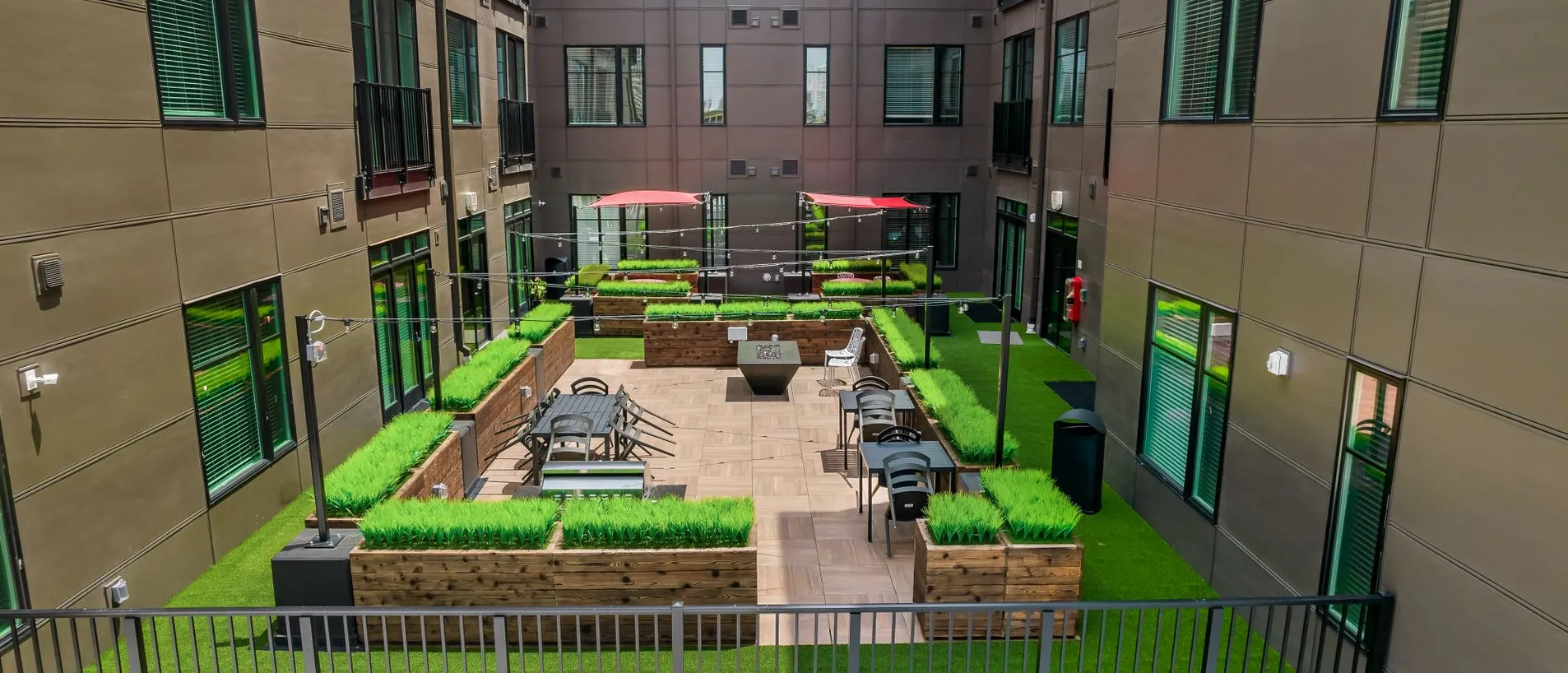 A courtyard featuring seating areas surrounded by greenery in an apartment complex.