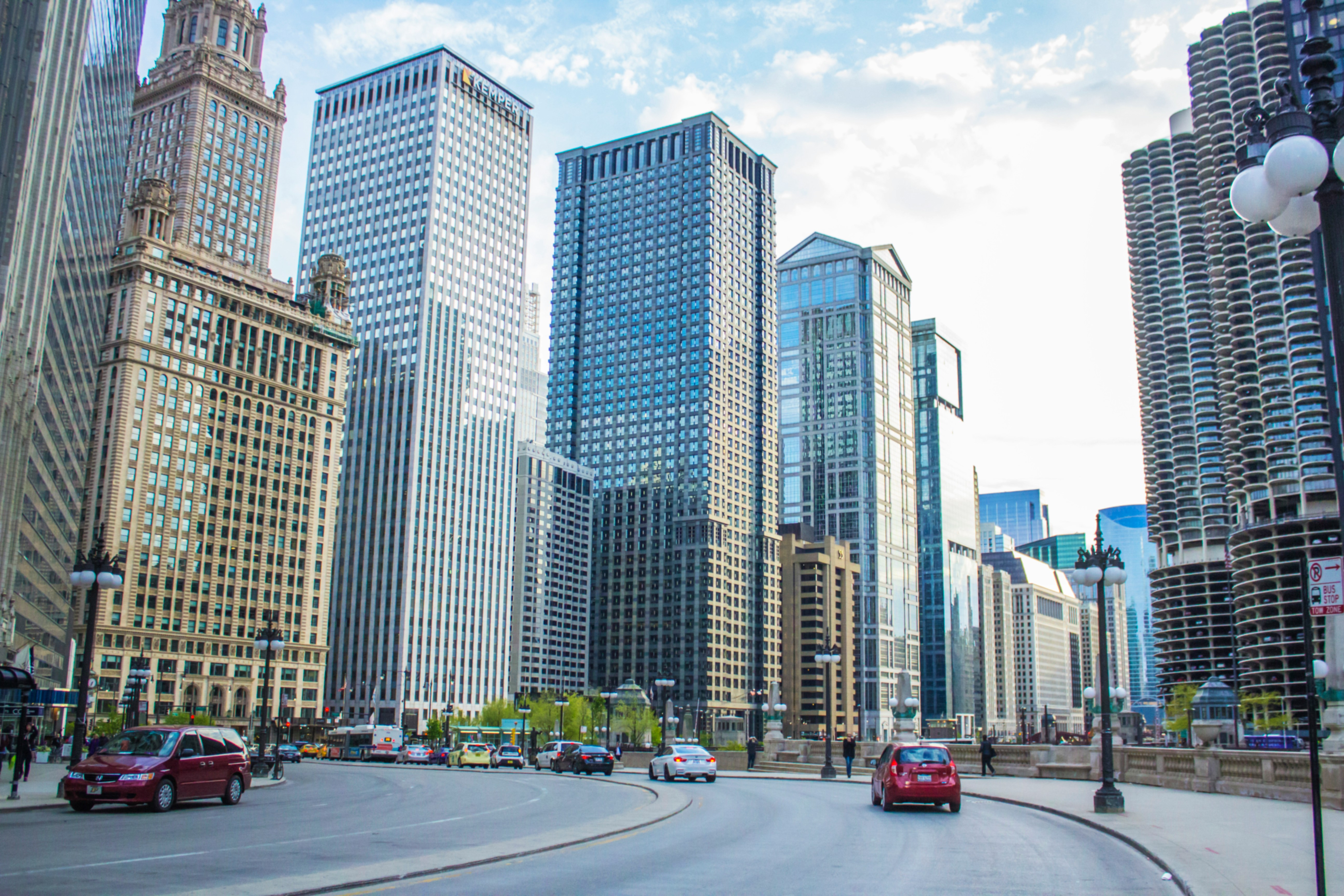 A view of tall skyscrapers in Chicago with a curve in the street and passing cars.
