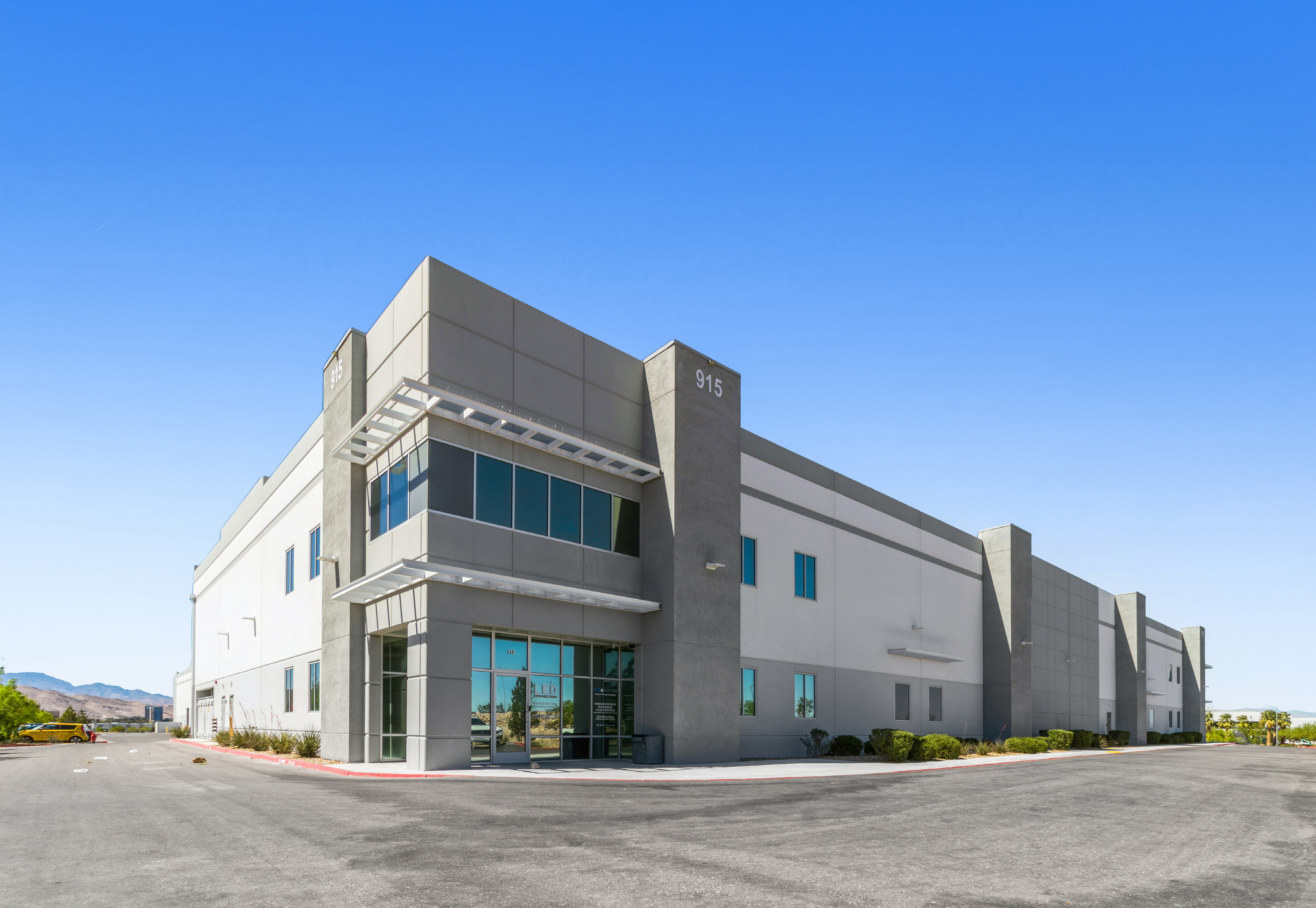 Exterior view of a modern commercial building with multiple windows and a clear blue sky in the background.