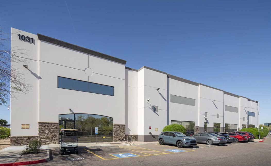A modern commercial building exterior with multiple parking spaces and a clear sky in the background.