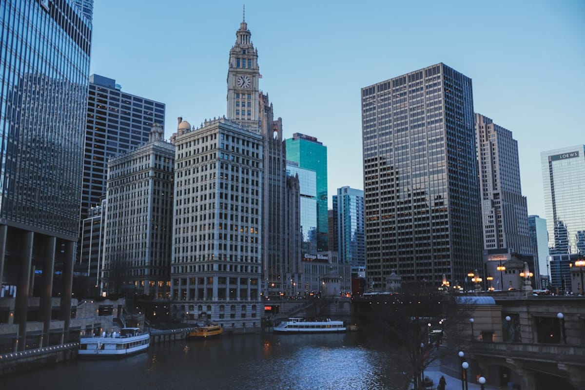 View of the Chicago river with skyscrapers on both sides and a historic clock tower building in the foreground.