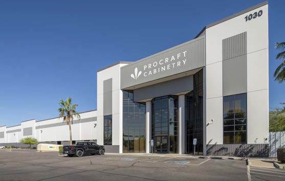 Exterior view of Procraft Cabinetry building with large glass entrance and palm trees nearby.