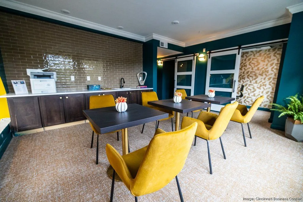A modern community lounge area with a kitchenette and dining tables