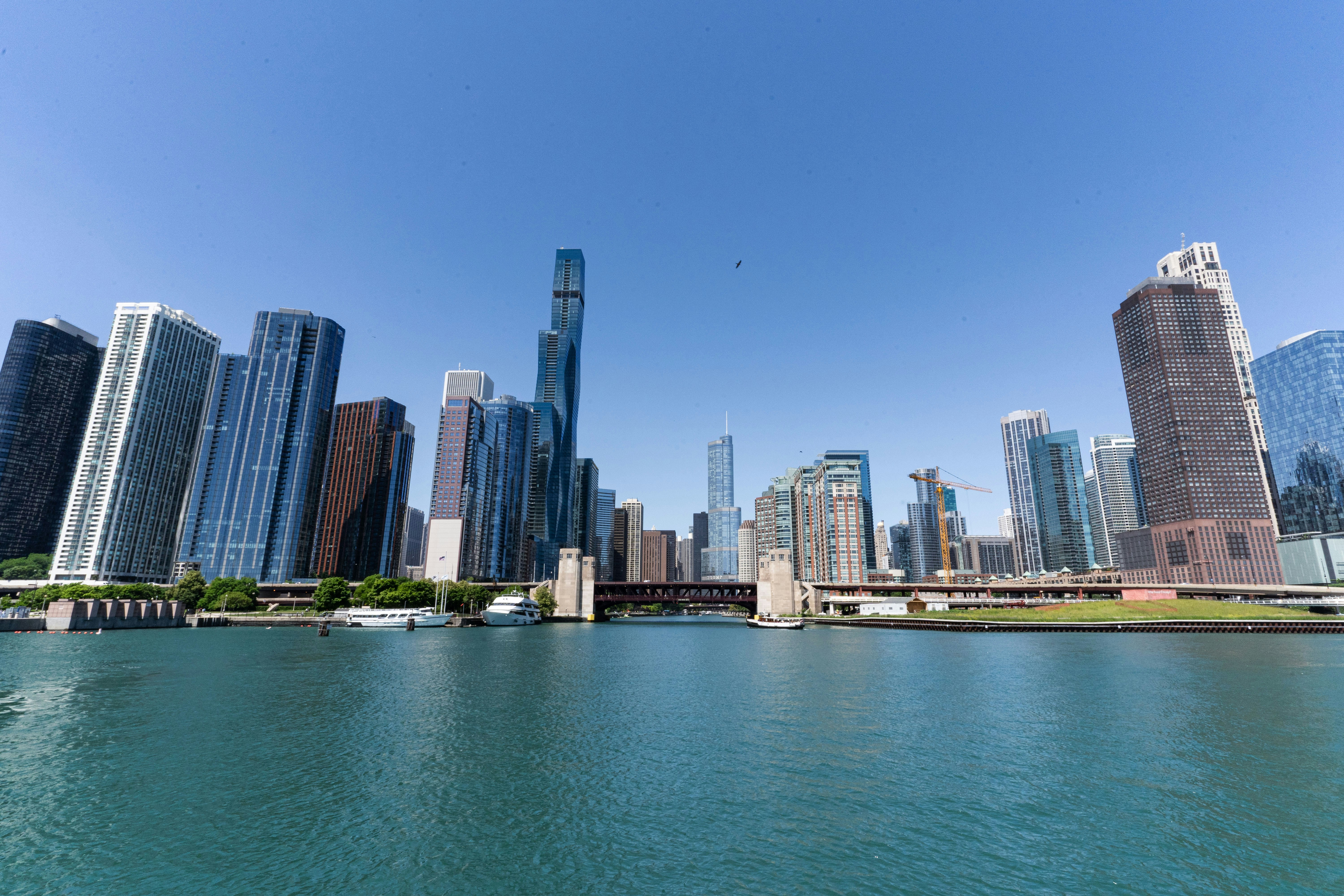 A panoramic view of the Chicago skyline from the river, showcasing a variety of high-rise buildings under a clear blue sky.