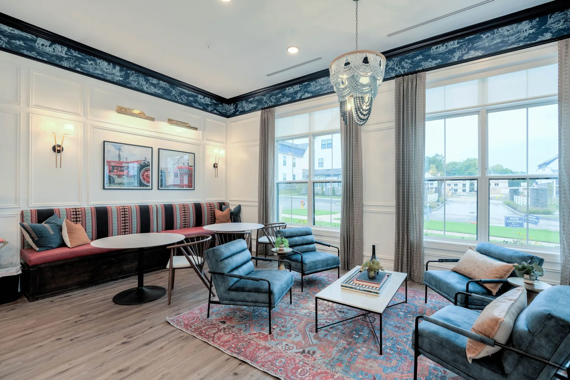 A stylish community lounge area featuring comfortable seating, decorative wall art, and large windows letting in natural light.