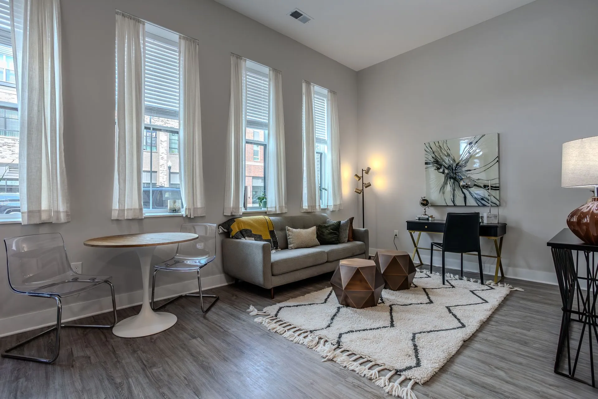 A modern living room with large windows, a sofa, and a workspace.