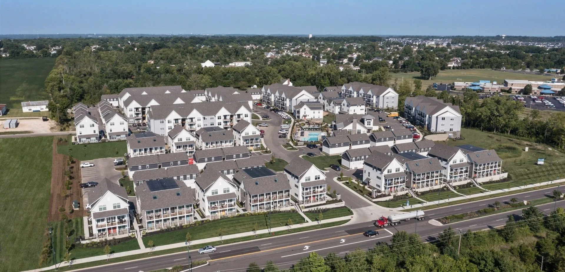 Aerial view of a modern apartment complex with multiple buildings, parking areas, and green spaces.