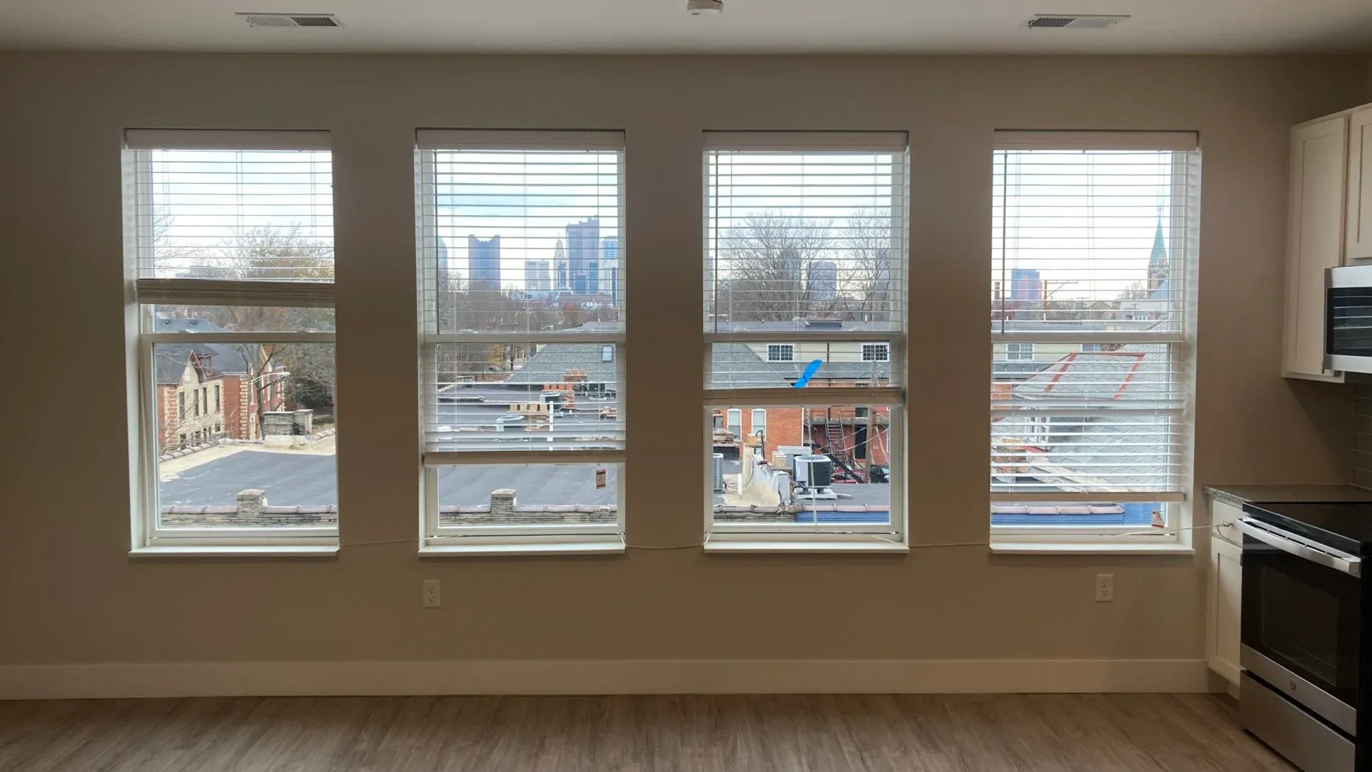 Interior view of a modern kitchen with four large windows showcasing a city skyline.