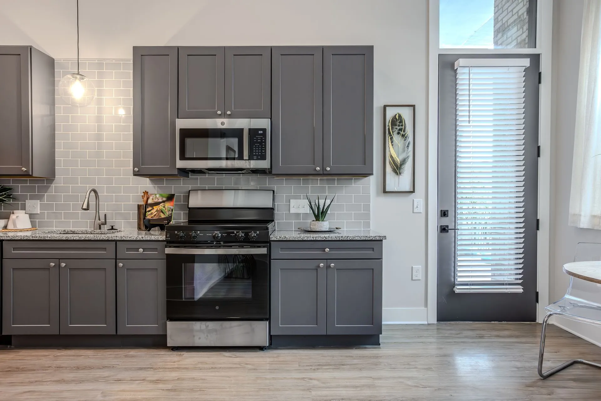 Modern kitchen featuring gray cabinets, stainless steel appliances, and a sleek countertop with a door leading outside.
