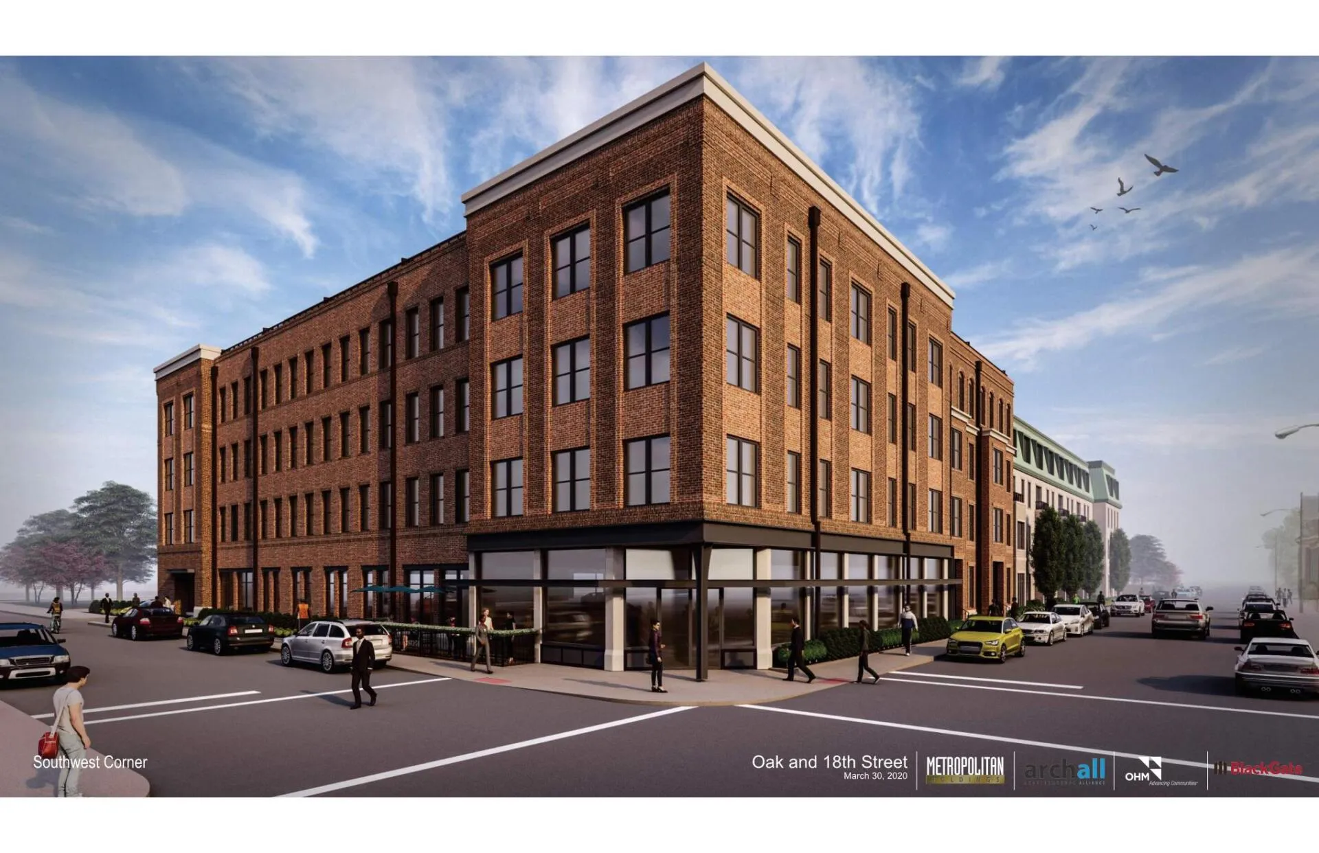 A modern brick building at the corner of Oak and 18th Street, featuring multiple windows and a storefront. There are cars parked along the street and pedestrians walking. A clear blue sky complements the scene.