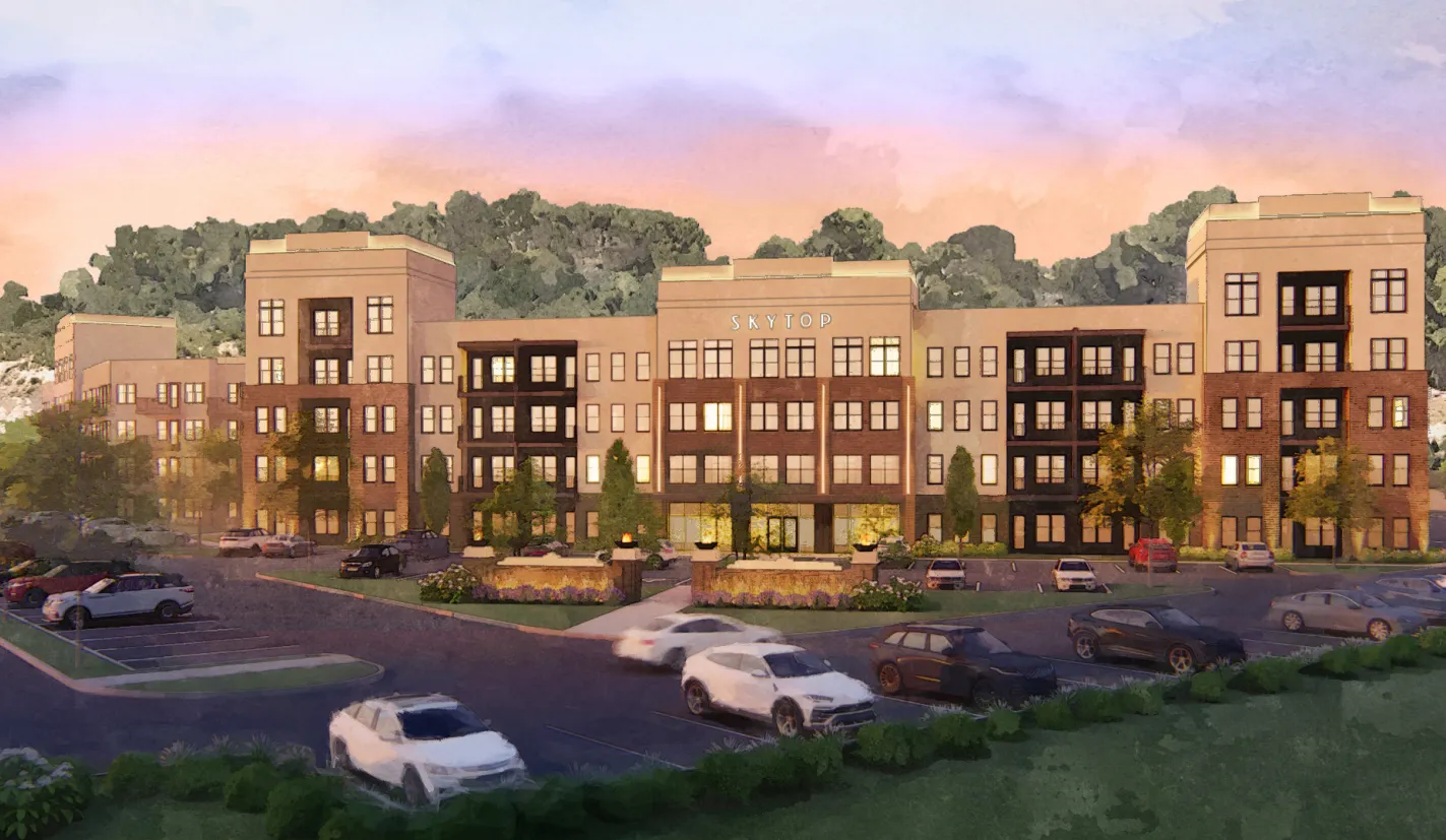 Exterior view of a modern apartment complex with parking and landscaped gardens at sunset.