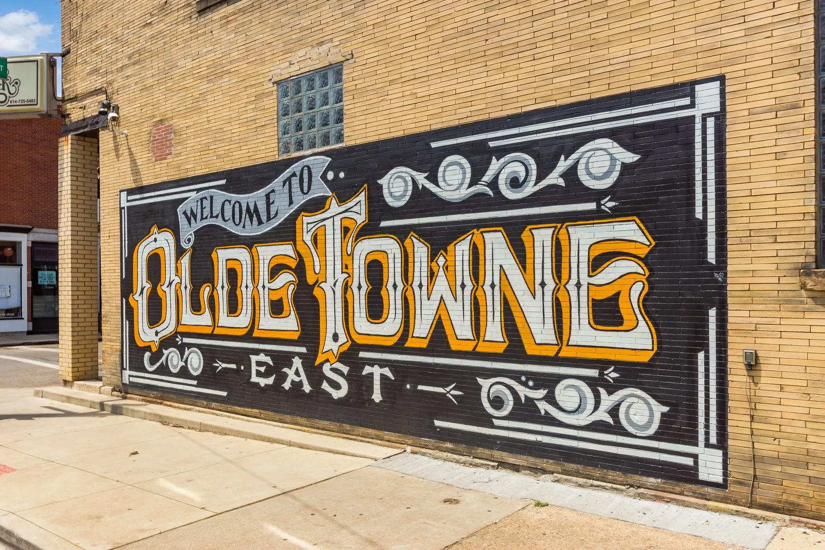 A mural on a brick wall that reads 'Welcome to Olde Towne East' in decorative lettering.