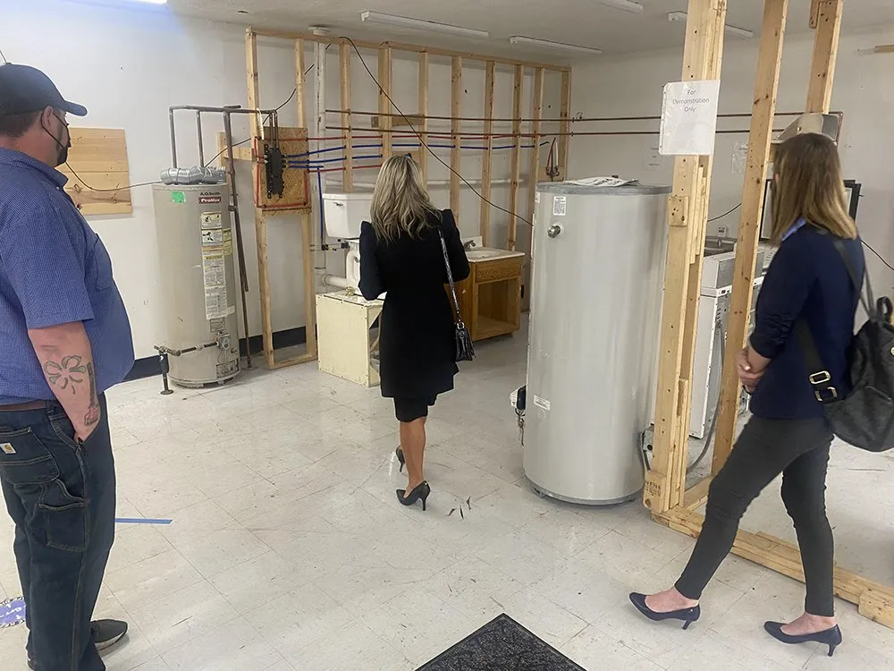 Group of individuals touring an unfinished space with appliances and temporary walls.