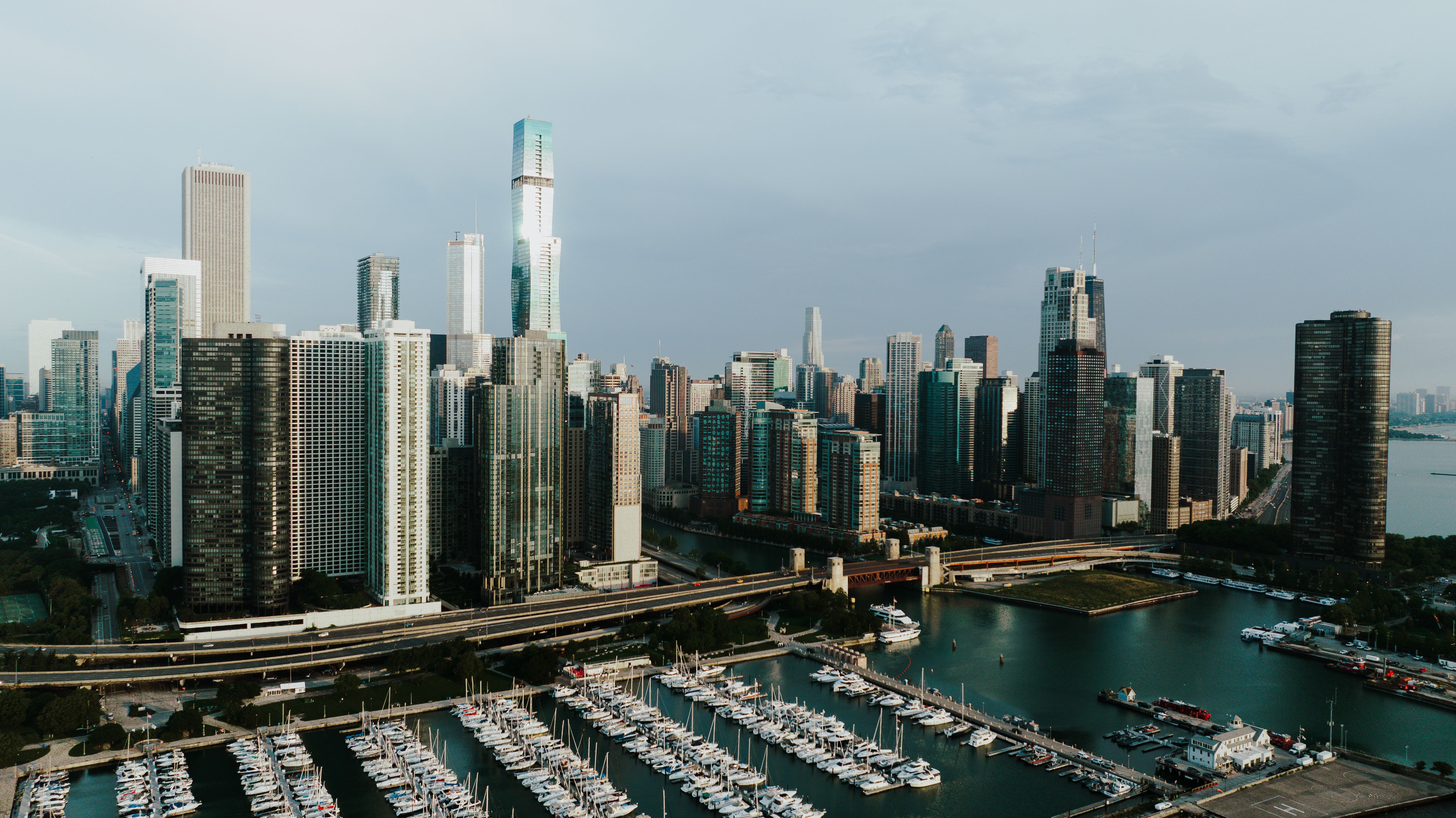 Aerial view of a modern city skyline with tall buildings, a marina, and a waterfront.