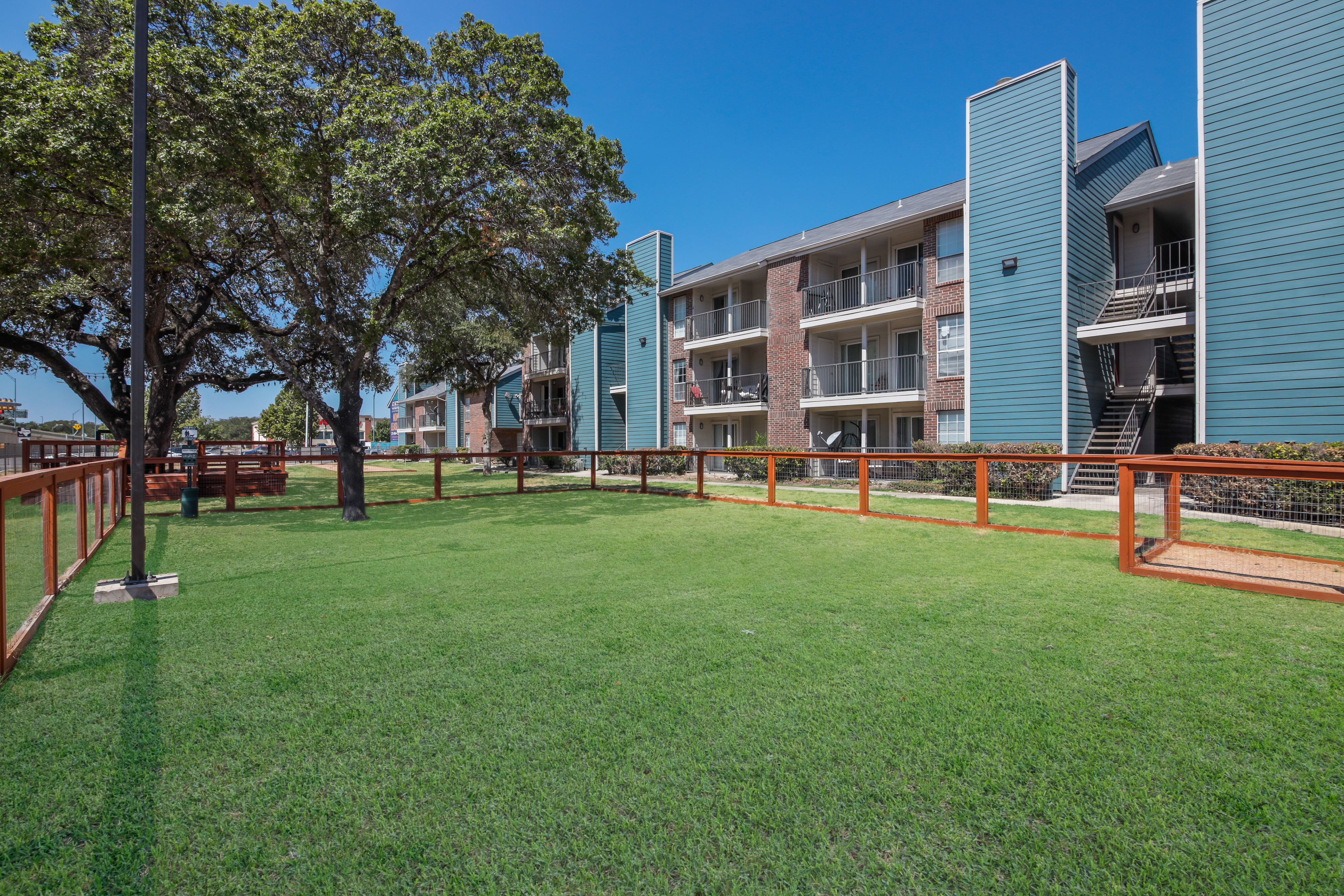 Exterior view of a residential apartment complex with green grass and trees.