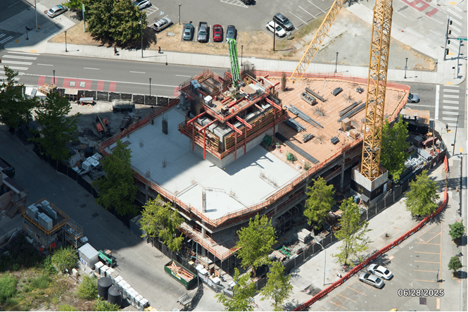 Aerial view of an active construction site with a partially completed building surrounded by various machinery and materials.