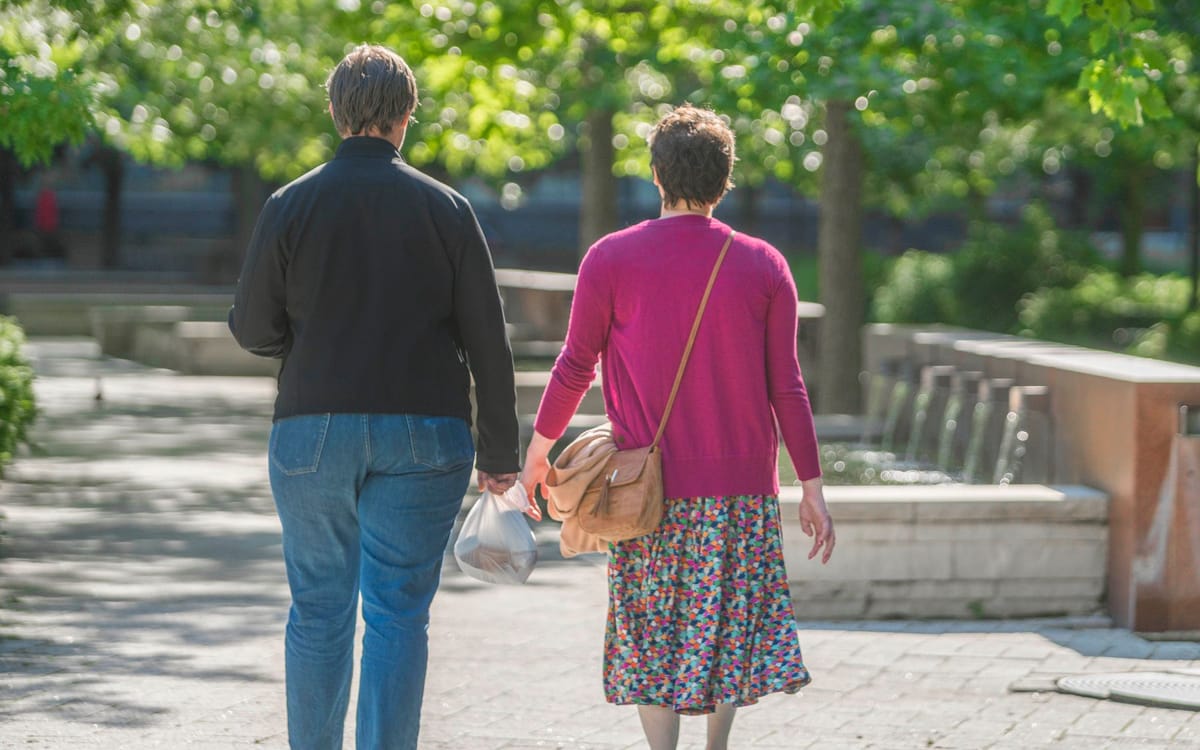 Why Residents Love Lakeshore East | Two people walking hand in hand on a sunny day amidst greenery.