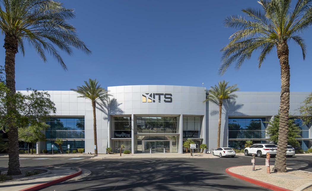 Modern commercial building with palm trees in front.