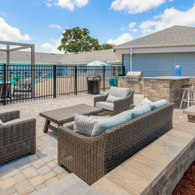 Cushioned patio furniture and grilling area by resident pool at Portofino Club.