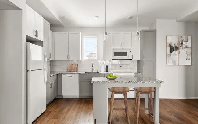 kitchen area with a wood tile floor, an island countertop with chairs, and white cabinets at apartment in Ewa Beach, HI - Room, Indoors, Flooring
