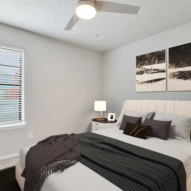 North Star Apartments bedroom with ceiling fan and carpeted flooring with grey walls and window
