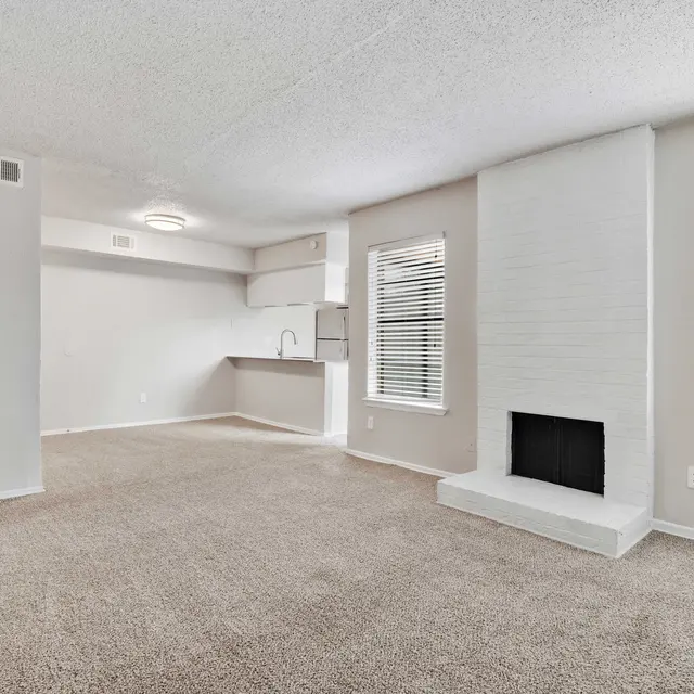 Apartment living and dining area with fireplace, carpeted flooring, and lots of windows with natural lighting at North Star Apartments