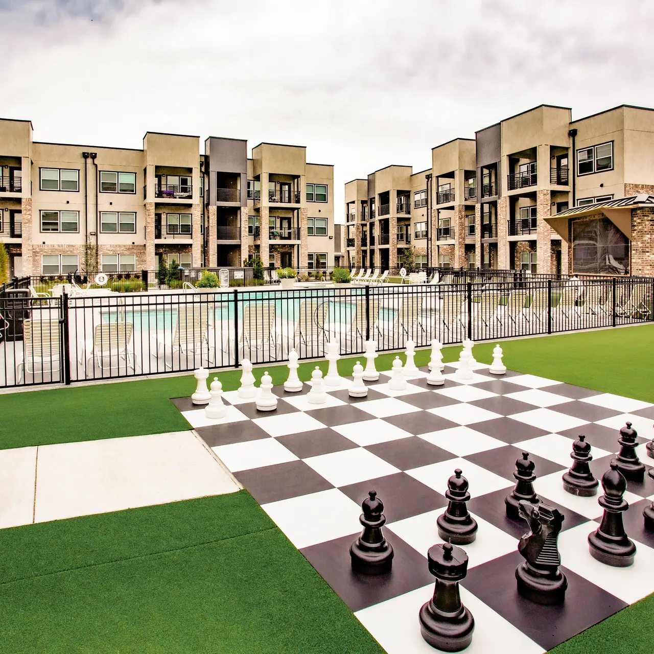 Courtyard Modern apartment complex with outdoor pool and large chessboard on grass.