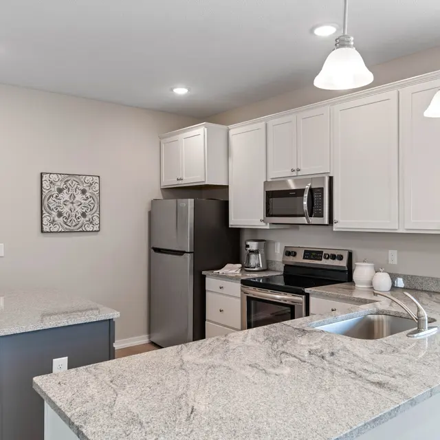 The Links at Franklin Apartments in Franklin, IN for Rent - The Links at Franklin - Modern Kitchen with Granite Countertops, White Shaker Cabinetry, Pendant Lights, Cooking Island with Stools, and Stainless Steel Appliances