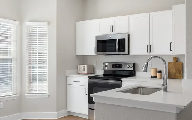 kitchen with white cabinetry,  white countertop,  and stainless steel appliances - Microwave, Oven, Appliance