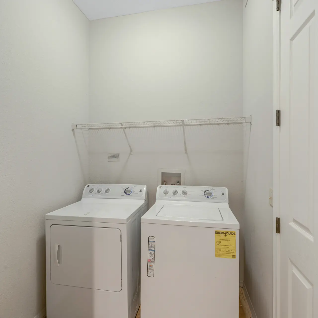 large laundry room with upper shelves for storage