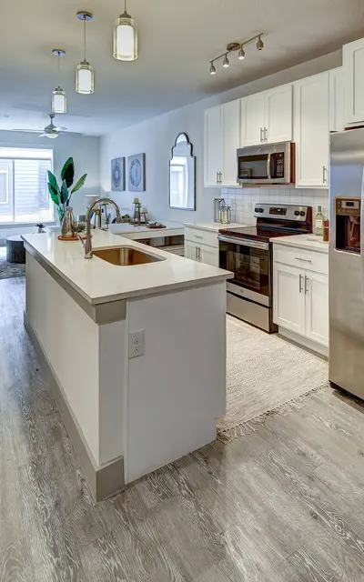 Apartment kitchen with white cabinets, stainless steel appliances, and a central island.