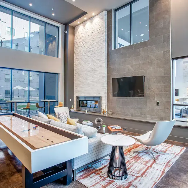 Modern Living Room Design A spacious modern living room with high ceilings, large windows, a stone fireplace, and contemporary furniture including an elegant coffee table and cozy seating arrangement.