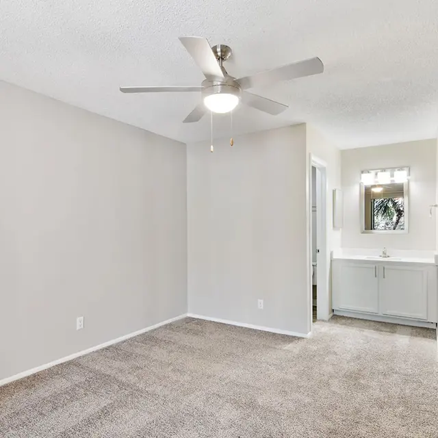 Venice Park bedroom with carpeted flooring, a ceiling fan, and a white vanity with a mirror above.