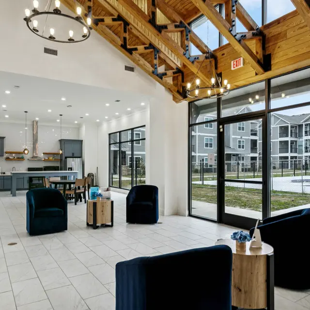 Spacious interior lounge area with high ceilings, featuring contemporary furniture and large windows overlooking an outdoor space.