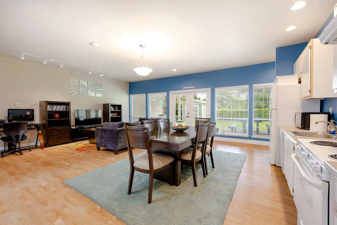 Modern Dining and Living Space A modern dining area featuring a large table with chairs, a seating area with a couch, and windows allowing ample natural light.