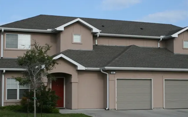 Residential House Exterior Two-story residential house with a light pink exterior and a dark gray roof.