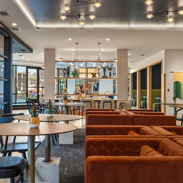 Interior view of a modern café featuring cozy seating, wooden tables, and shelves with decorative items.