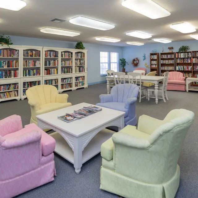 Interior of a cozy library with pastel-colored armchairs and bookshelves filled with books.