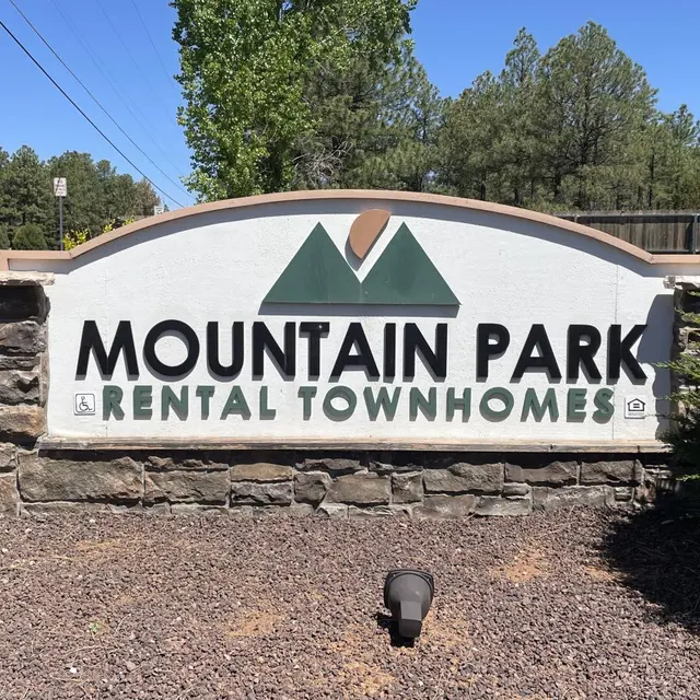 Mountain Park Rental Townhomes Sign Sign for Mountain Park Rental Townhomes with a stylized mountain graphic, surrounded by trees.