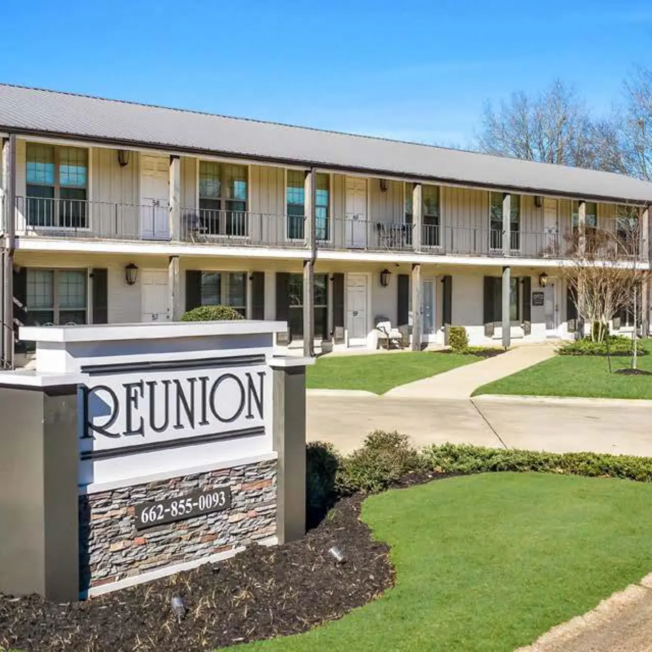 Exterior view of a two-story motel named 'Reunion', featuring balconies and a well-maintained lawn area.