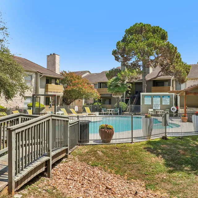 Community Pool Area in Apartment Complex A community pool area surrounded by apartment buildings, with lounge chairs and a shaded gazebo.