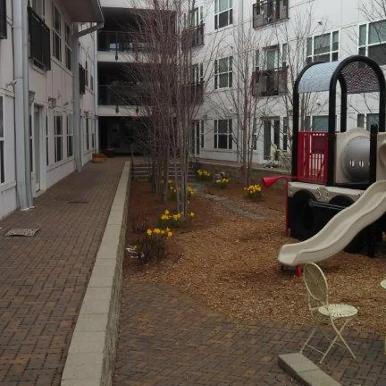 A courtyard area with a playground slide and yellow flowers