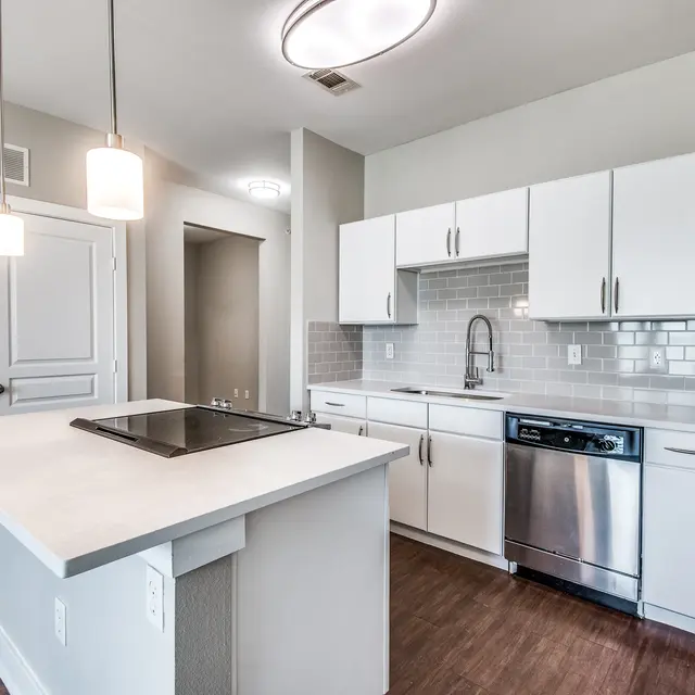Centreport Lake Kitchen and center island with the stove on hardwood-style flooring, with white cabinets and stainless-steel appliances.