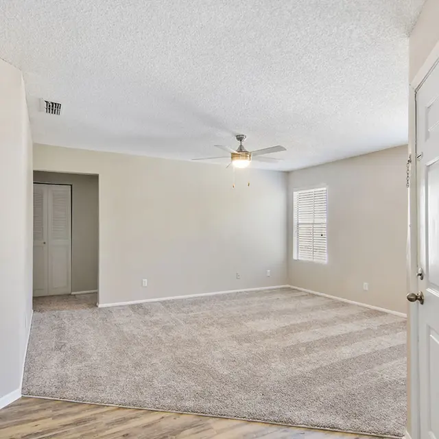 Living room with carpeted flooring, a ceiling fan, and a window for natural light.