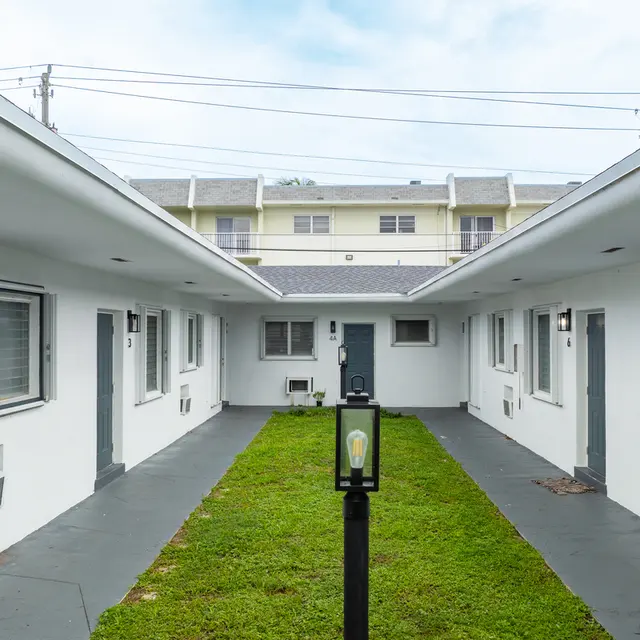 View of a motel courtyard with white buildings and a grassy area in the center.