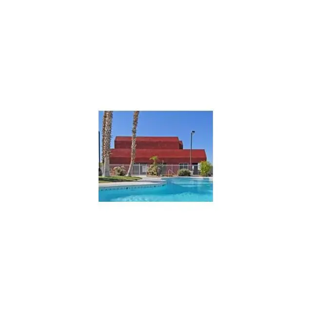 Poolside View with Red Roof Building A view of a swimming pool with a red-roofed building in the background, surrounded by palm trees.