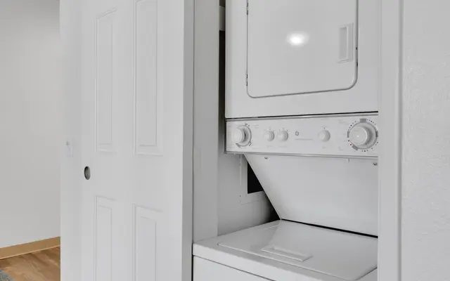 A compact laundry area featuring a stacked washing machine and dryer behind sliding doors.