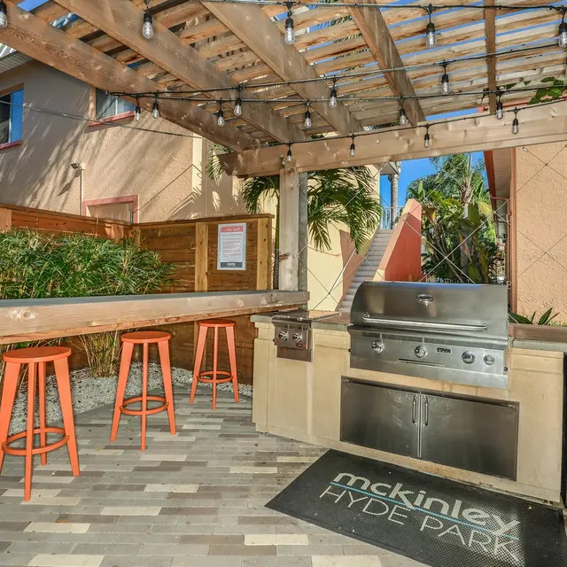 Outdoor grill area with bar seating under a wooden pergola