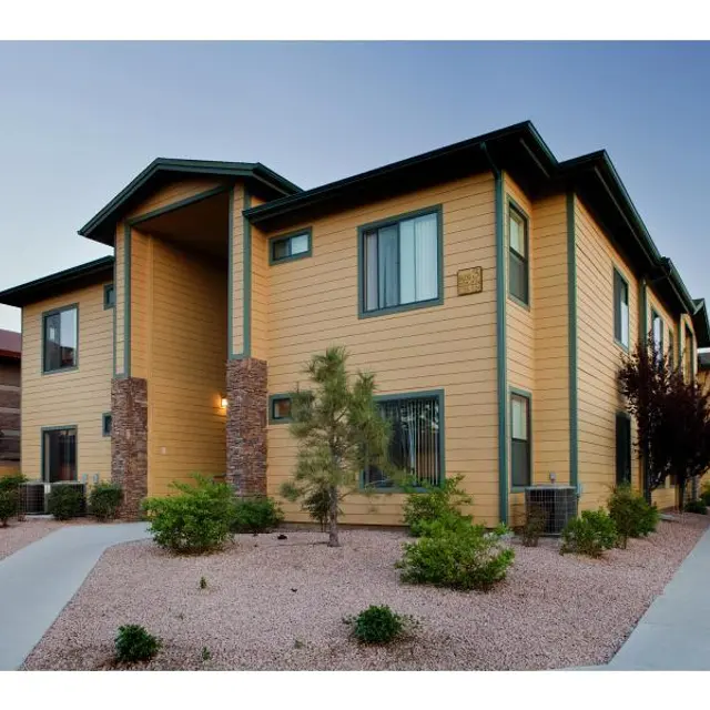 Modern Apartment Building A modern apartment building with a yellow exterior and landscaping including small trees and shrubs.