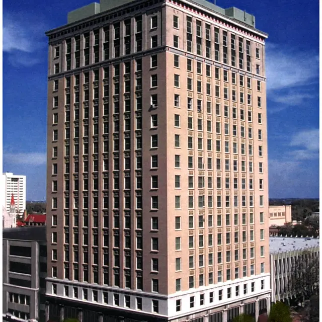 Historic Building Downtown A tall historic building with a classic style, featuring a prominent tower, multiple windows, and a ground floor with awnings and trees.